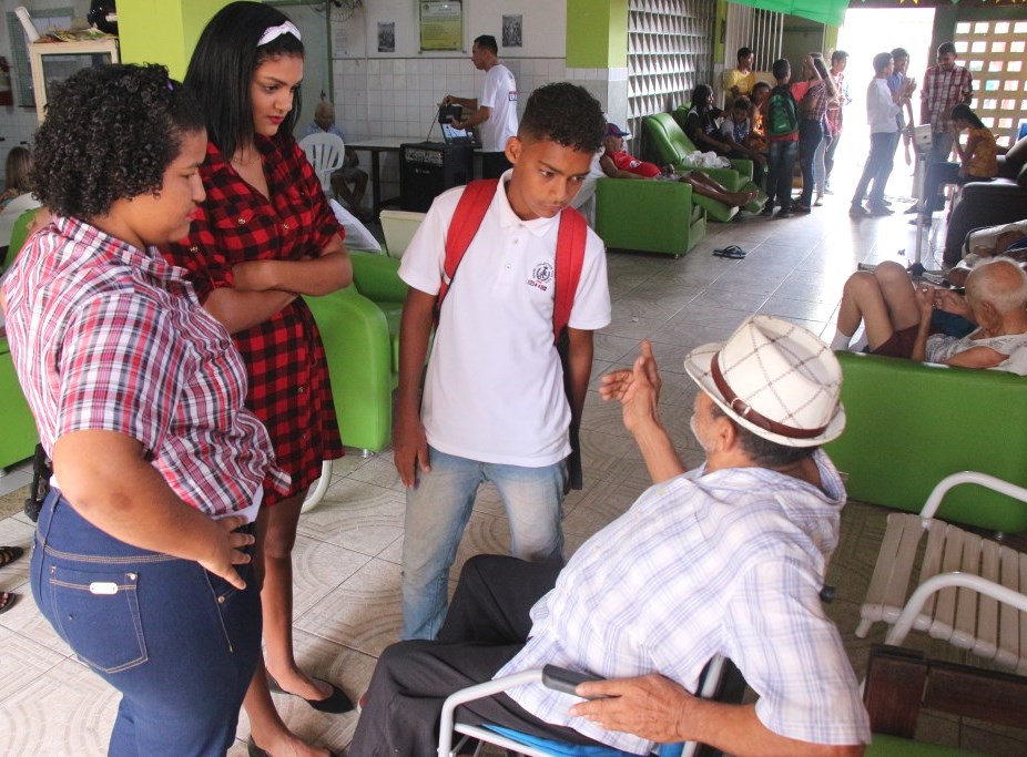 Estudantes Joyce Camile  e Cauã de Lima conversam com José Domingos da Silva, de 70 anos.  