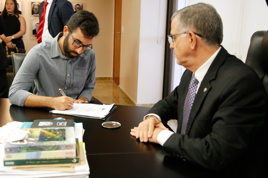 Carlos Adolfo assina termo de posse, ao do do desembargador Sebastião Costa.