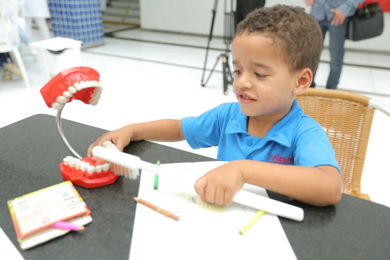 Criança recebia orientação de alunos da Unit sobre como escovar os dentes.
